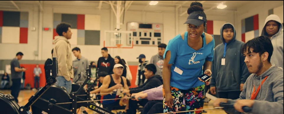 Group rowing in a busy gym setting.